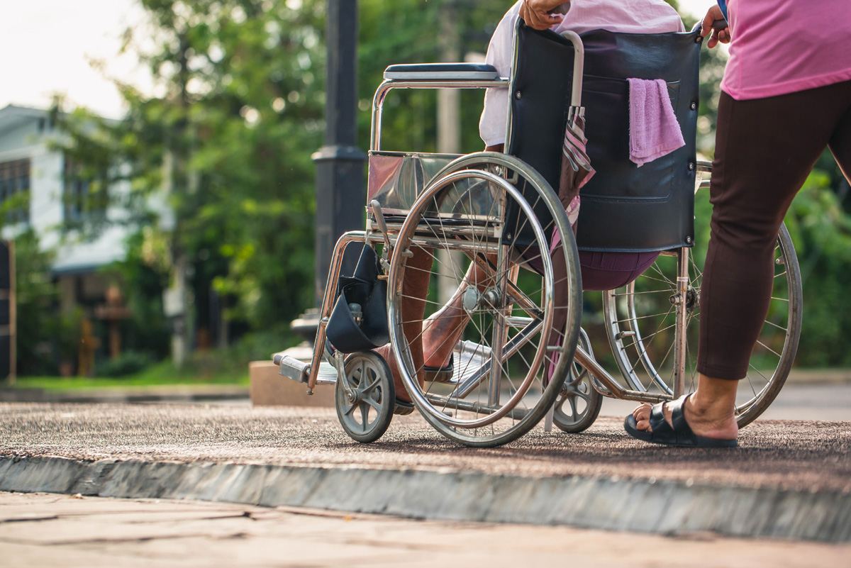 Disabled mature senior man in a wheelchair relaxing in a park by Disabled mature senior man in a wheelchair relaxing in a park by his wife take care with sunset background. Senior man and woman in wheelchair in autumn nature.